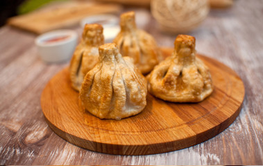Fototapeta na wymiar fried khinkali on a wooden tray photo in cream tones