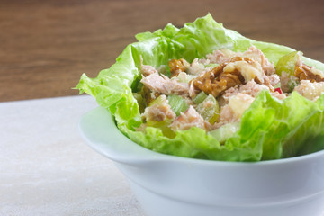 Homemade waldorf salad made of celery, apples and walnuts, served on a bed of fresh leaf lettuce.