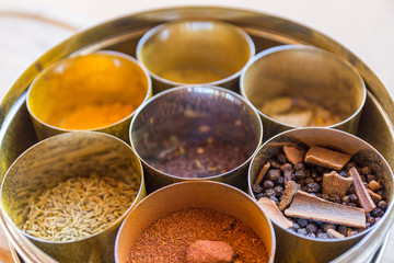close-up of metal canisters with spices of different colors and textures