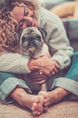 Love and friendship concept with happy defocused caucasian adult woman hug her lovely old dog pug -...