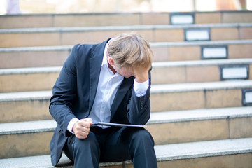 unemployed businessman sitting with sadness on stair, concept of business failure and unemployment problem.