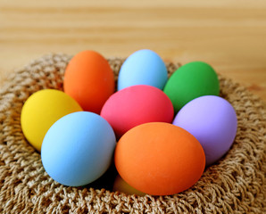 Fototapeta na wymiar Closeup a Basket of Multi-color Easter Eggs on Wooden Table 