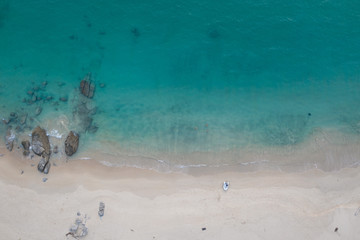 Aerial drone top view of tropical empty beach with turquoise sea water and rocks