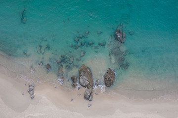 Aerial drone top view of tropical empty beach with turquoise sea water and rocks