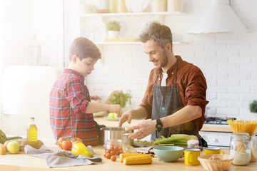 Father and son spanding time together and cooking at home kitchen. 
