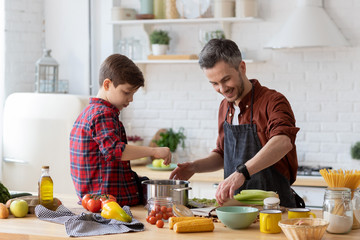 Father and son prepare dinner together at home kitchen. 