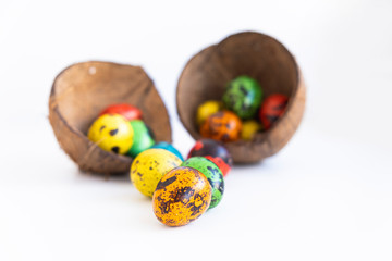 Bright orange quail egg painted for Easter on a blurry background of coconut shell.