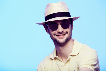 Closeup portrait of awesome hipster wearing fedora hat with intense look at camera. Headshot over blue studio background. - obrazy, fototapety, plakaty