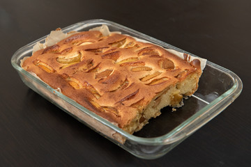 a slice of apple pie on a dark kitchen table in a glass form