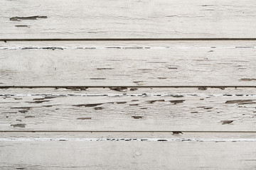 Wooden wall with bits and pieces of paint peeling off in a bright white color.