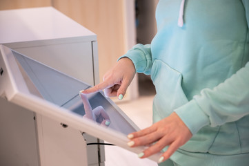 Faceless woman touching the screen of a self-service device in a store. Device store navigator....