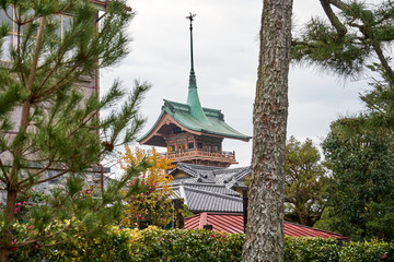 Naklejka premium Temple with a tall spike on their roof through the gap between trees