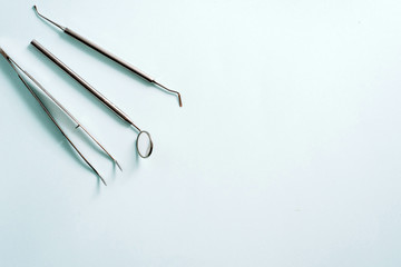 Dental tools on a blue background. Dental mirror and tweezers, dental treatment concept