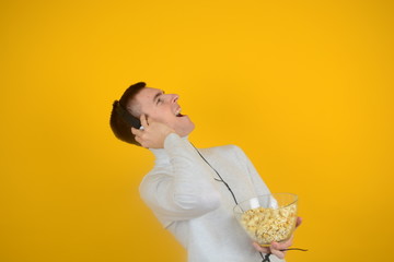 man sings songs listens to music on headphones with popcorn on yellow background weekend
