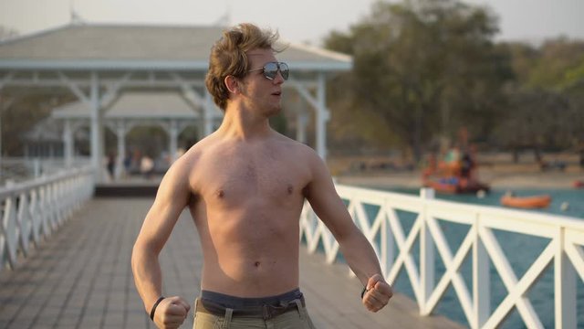 Shirtless Young Man Flexing Muscles Outdoors