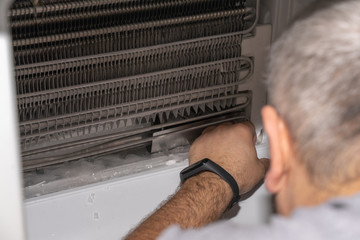 master removed the refrigerator freezer fan for repair, looks at the cooling radiator, removes ice