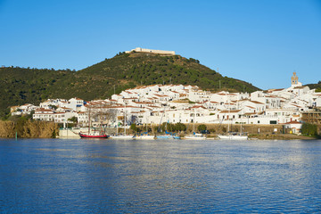 Fototapeta na wymiar Sanlucar de Guadiana in Spain and Alcoutim in Portugal with sail boats on Guadiana river
