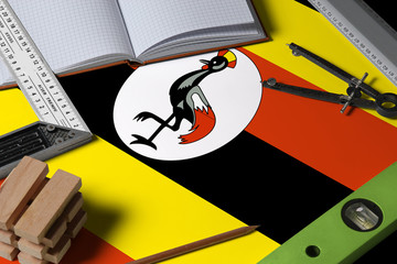 Uganda national flag on profession concept with architect desk and tools background. Top view mock-up.