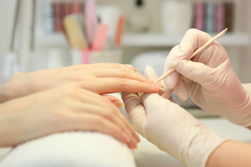 Closeup shot of a woman in a nail salon getting a manicure by a cosmetologist with a nail file. Woman gets a manicure of nails. Beautician puts nails on the client.
 - obrazy, fototapety, plakaty