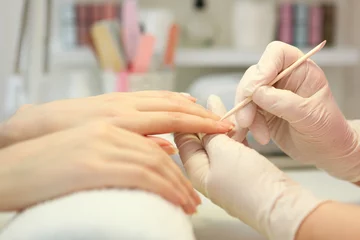  Closeup shot of a woman in a nail salon getting a manicure by a cosmetologist with a nail file. Woman gets a manicure of nails. Beautician puts nails on the client.  © White bear studio 