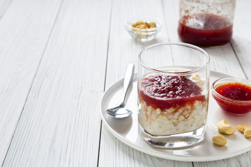 Oatmeal with milk and strawberry jam in glass on white wooden table. healthy organic food. breakfast. copy space