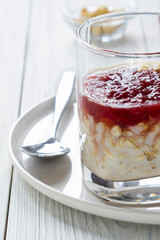 Oatmeal with milk and strawberry jam in glass on white wooden table. healthy organic food. breakfast. close up. vertical layout