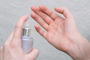 Hand sanitizer treatment. Girl sprays an antiseptic in her hands.