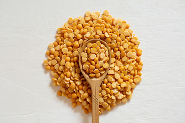 Yellow split peas in a spoon on a white background. Dry cereal for cooking.