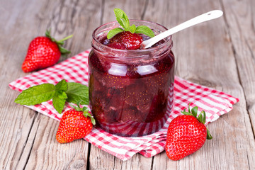 Homemade delicious strawberry jam and strawberry on a rustic wooden table