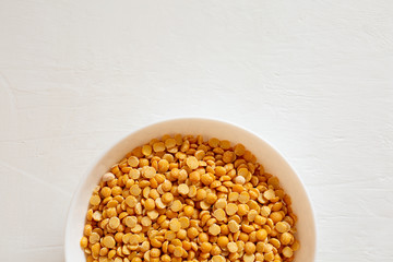 Yellow split peas in a bowl on a white background. Dry cereal for cooking.