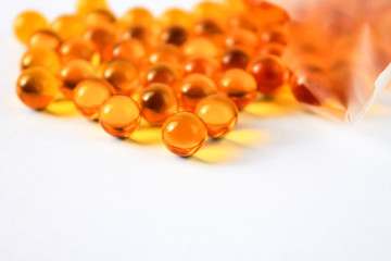 Yellow capsules of vitamins lie on a table on a white background for immunity and disease prevention