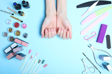 Hands care. Top view of the hands of a beautiful smooth woman with professional nail care tools for manicure on a colored background.
