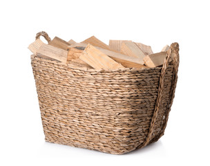 Obraz premium Wicker basket with cut firewood isolated on white