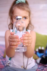 Caucasian cute little girl holding a potion in a glass bottle at home, playing doctor. Quarantine protection against coronavirus 2019-nkov. Home insulation. Close-up