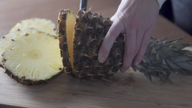 A woman's hand cuts pineapple rings,