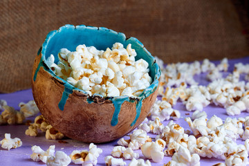 Popcorn in brown handmade clay bowl on purple wooden table