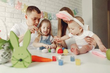 Parents and daughter paint eggs. Family in a kitchen. Preparing for Easter