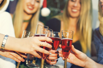 Cheers! Girls friends having xmas party and drinking red shampagne. Toasting with glasses of wine on the smiling womans backgroung. New year party