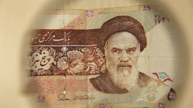View a Five thousand Iranian rials bill lying on a table with a magnifying glass. concept of business and finance. Obverse