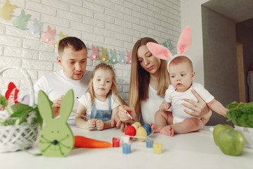 Parents and daughter paint eggs. Family in a kitchen. Preparing for Easter