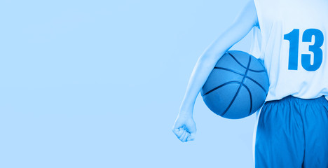 Rear view of a basketball player holding a ball. Blue filter