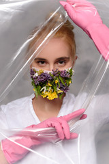 Quarantined woman wears a protective mask of flowers.
Quarantined woman breakthrough of oilcloth.