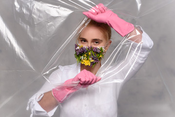 Quarantined woman wears a protective mask of flowers.
Quarantined woman breakthrough of oilcloth.