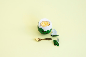 Boiled green quail egg peeled next to a small spoon close-up on a yellow background.