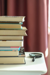 What to read in quarantine? A selection of books. A stack of books on a nightstand by the window in...