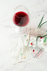 preparations, pills and a thermometer and a glass of red wine on a white background
