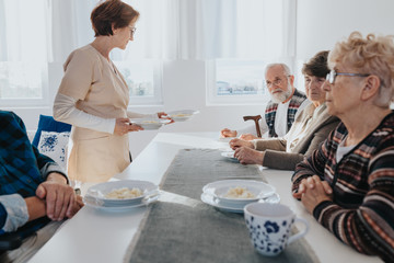 Senior patients and nurse in local nursing home during dinner time