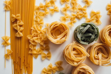 Varieties of Italian pasta. Spaghetti, farfalle and tagliatelle isolated on a white background, top view. Non-perishable food