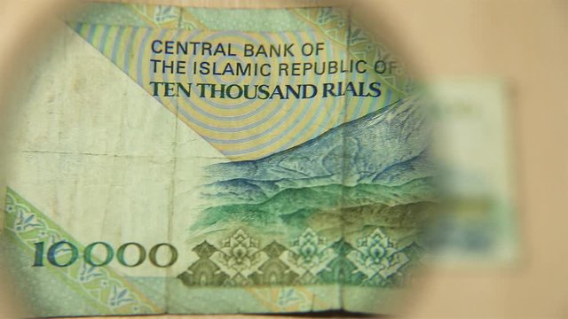 View a Ten thousand Iranian rials bill lying on a table with a magnifying glass. concept of business and finance. reverse side