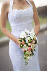 Obraz na płótnie Canvas Bride in white dress holds a beautiful bouquet cascade
